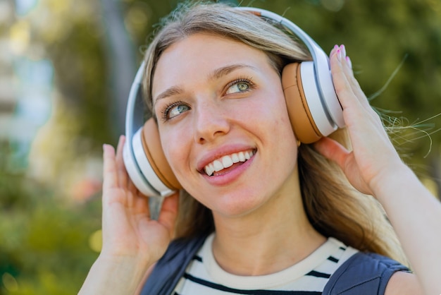 Foto jonge blonde vrouw die buitenshuis muziek luistert