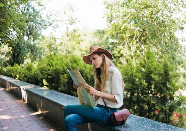 Jonge blonde vrouw die de stadsplattegrond kijkt