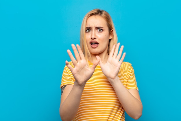 Jonge blonde vrouw die doodsbang was, deinsde terug en schreeuwde van afgrijzen en paniek, reagerend op een nachtmerrie