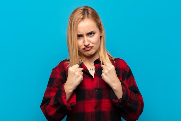 Foto jonge blonde vrouw die er zelfverzekerd, boos, sterk en agressief uitziet, met vuisten klaar om te vechten in bokspositie