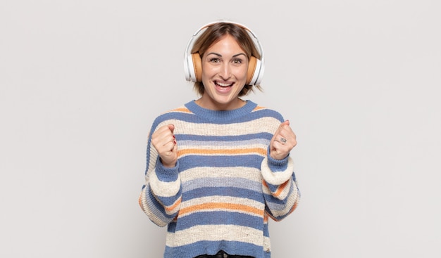 Jonge blonde vrouw die geschokt, opgewonden en gelukkig voelt, lacht en succes viert, zeggend wow!