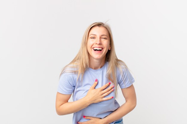 Jonge blonde vrouw die hardop lacht om een hilarische grap