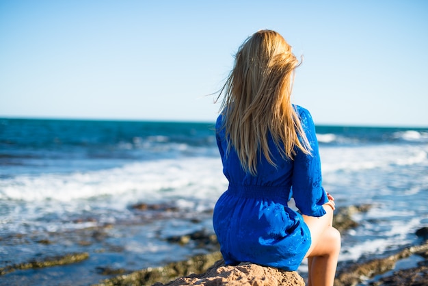 Jonge blonde vrouw die het overzees toont