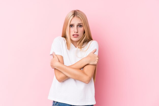 Jonge blonde vrouw die koud wordt door een lage temperatuur of een ziekte.