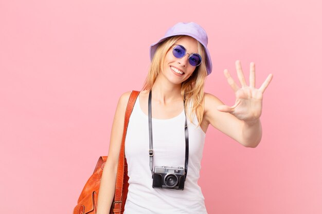 Jonge blonde vrouw die lacht en er vriendelijk uitziet, met nummer vijf