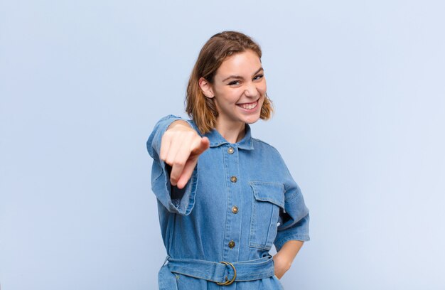 Jonge blonde vrouw die met een tevreden, zekere, vriendschappelijke glimlach richt, die u over muur kiest