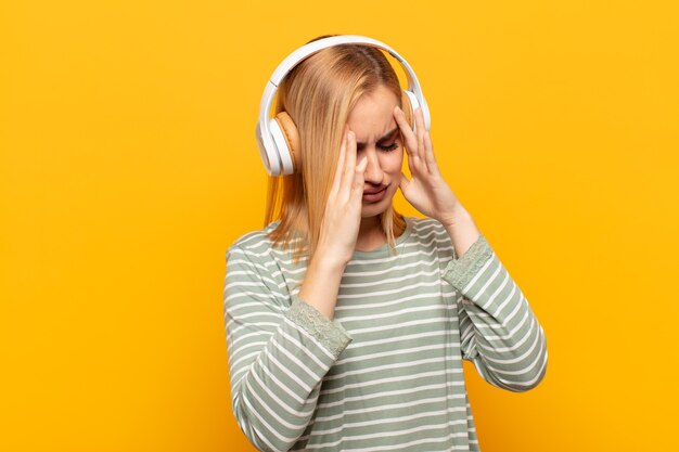 Jonge blonde vrouw die ogen bedekt met handen met een droevige, gefrustreerde blik van wanhoop, huilend, zijaanzicht