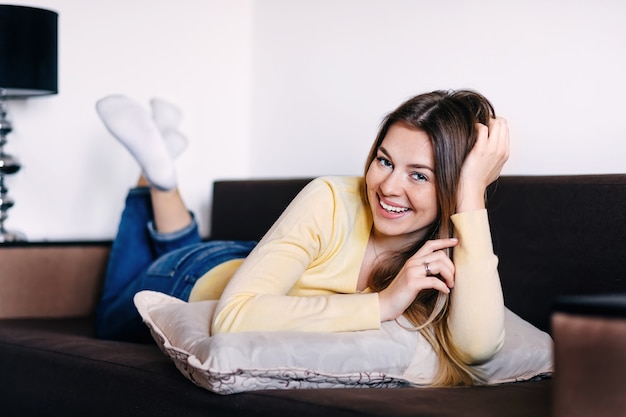 Jonge blonde vrouw die op de bank ligt