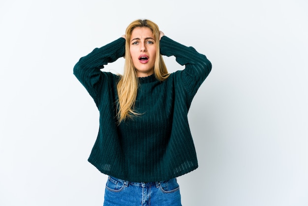 Jonge blonde vrouw die op wit wordt geïsoleerd dat met woede gilt.