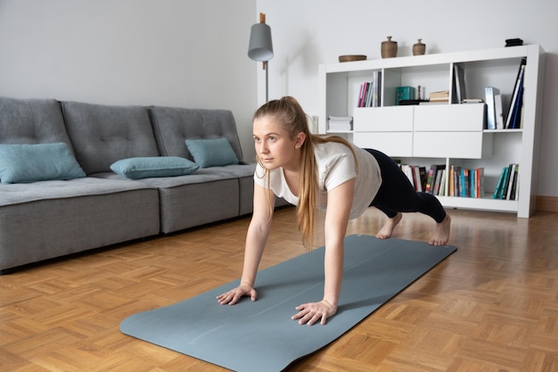 Jonge blonde vrouw die thuis aan het trainen is Tiener die pushups maakt