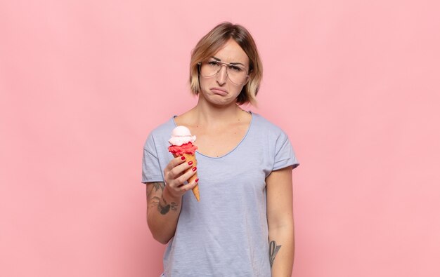 Jonge blonde vrouw die verdrietig en zeurderig is met een ongelukkige blik, huilend met een negatieve en gefrustreerde houding