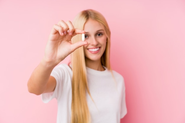 Jonge blonde vrouw die wat geïsoleerde pillen neemt