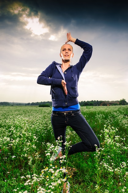 Foto jonge blonde vrouw die yoga op een weide doet