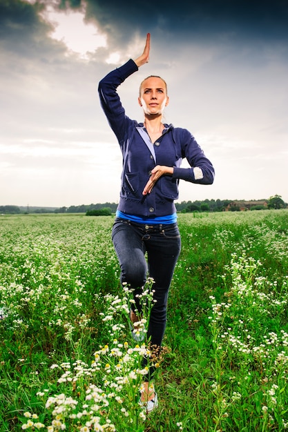 Jonge blonde vrouw die yoga op een weide doet