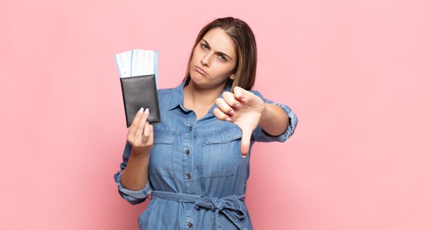 Jonge blonde vrouw die zich boos, boos, geïrriteerd, teleurgesteld of ontevreden voelt, duimen naar beneden toont met een serieuze blik