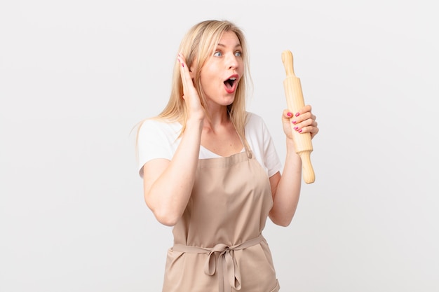 Jonge blonde vrouw die zich gelukkig, opgewonden en verrast voelt. bakker concept