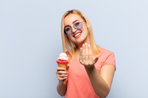 Jonge blonde vrouw die zich gelukkig, succesvol en zelfverzekerd voelt, een uitdaging aangaat en zegt: kom maar op! of je verwelkomen