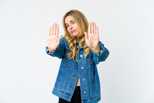 Jonge blonde vrouw die zich met uitgestrekte hand bevindt die stopbord toont