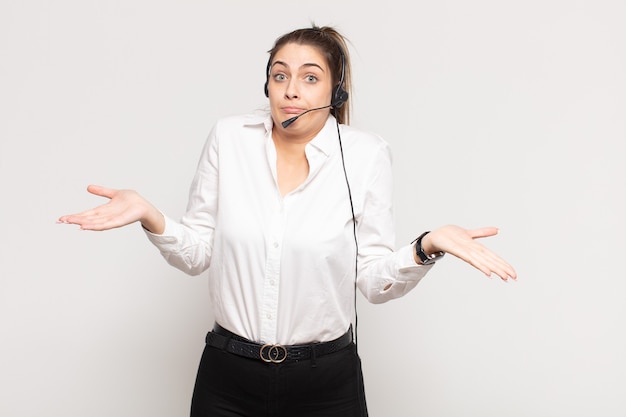 Jonge blonde vrouw die zich verbaasd en verward voelt, twijfelt, weegt of verschillende opties kiest met grappige uitdrukking