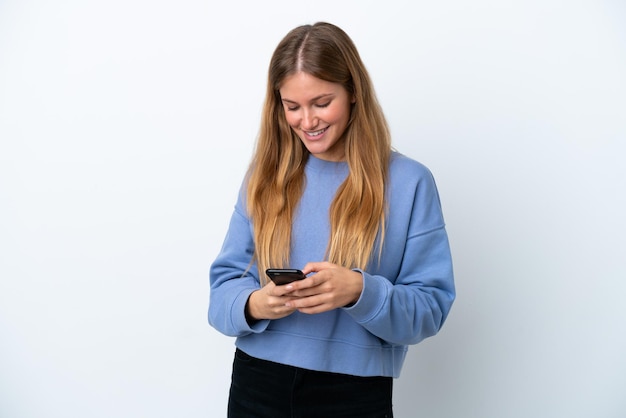 Jonge blonde vrouw geïsoleerd op een witte achtergrond die een bericht verzendt met de mobiel