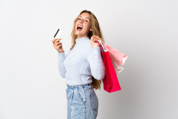 Jonge blonde vrouw geïsoleerd op een witte achtergrond met boodschappentassen en een creditcard