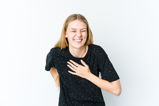 Jonge blonde vrouw geïsoleerd op een witte muur lachen houden handen op hart