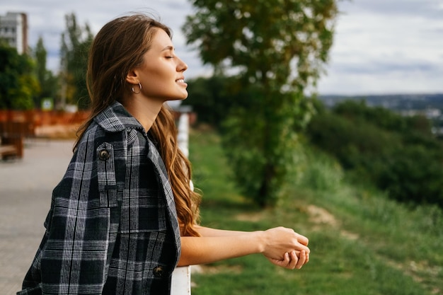 Foto jonge blonde vrouw geniet van een zonnige, winderige dag met gesloten ogen buitenshuis