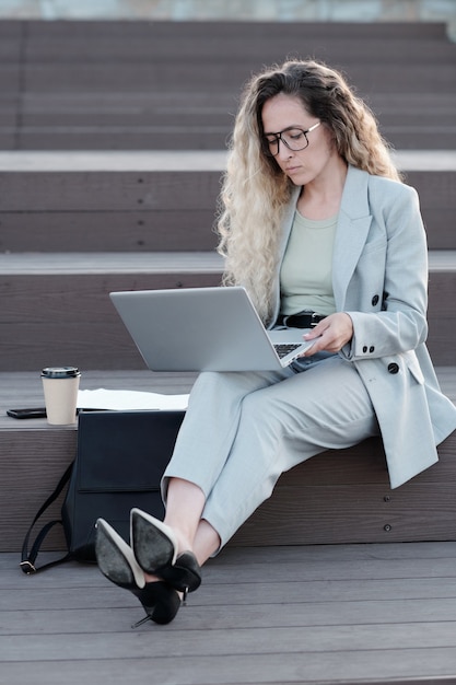 Jonge blonde vrouw in pak kijken naar laptopscherm