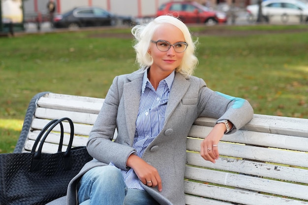 Jonge blonde vrouw met behulp van een slimme telefoon buitenshuis herfstdag