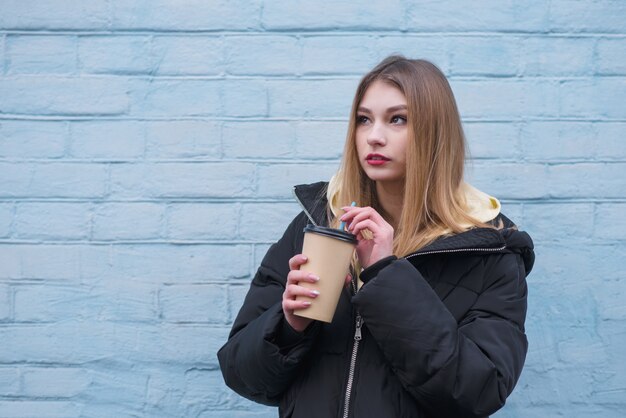 Jonge blonde vrouw met een glas warme drank