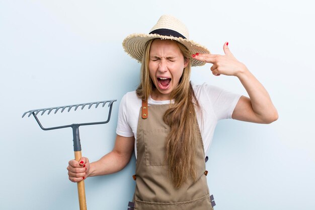 Jonge blonde vrouw met een hark boer concept