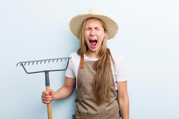 Foto jonge blonde vrouw met een hark boer concept