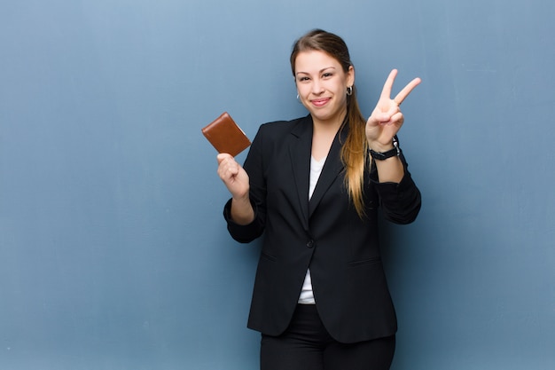 Jonge blonde vrouw met een portefeuille tegen grungemuur