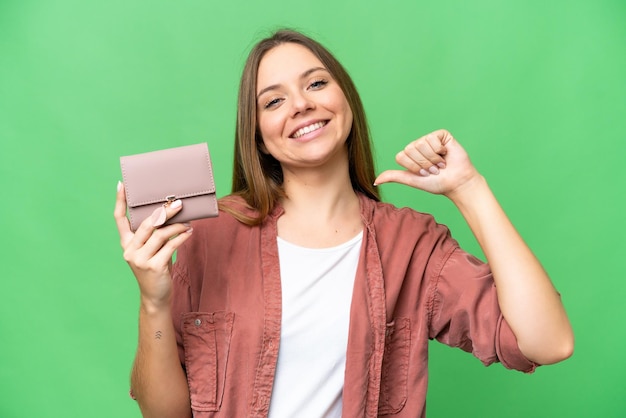 Jonge blonde vrouw met een portemonnee over geïsoleerde chroma key achtergrond trots en zelfvoldaan