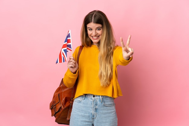 Jonge blonde vrouw met een vlag van het Verenigd Koninkrijk geïsoleerd glimlachen