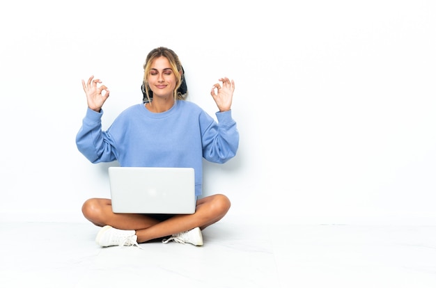 Jonge blonde vrouw met laptop geïsoleerd in zen pose