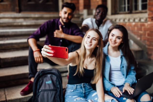 Jonge blonde vrouw selfie maken met haar vrienden studenten in universit