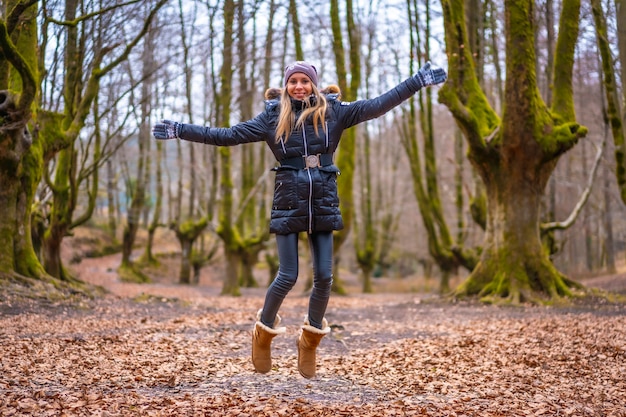 jonge blonde vrouw springen in een bos in de herfst