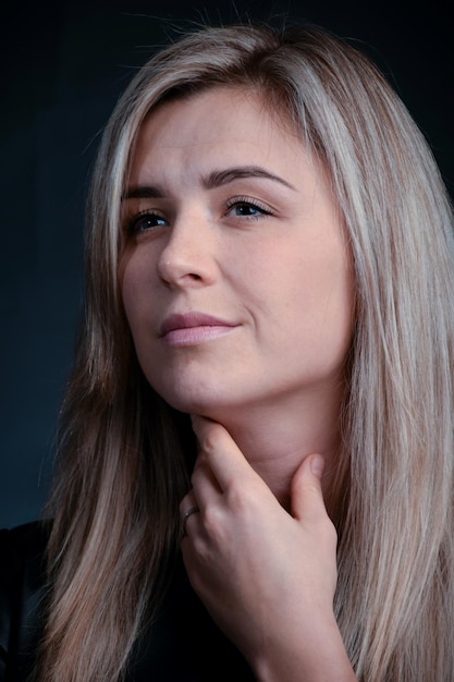 Jonge blonde vrouw van blank ras met lang haar Studio foto op een donkere achtergrond