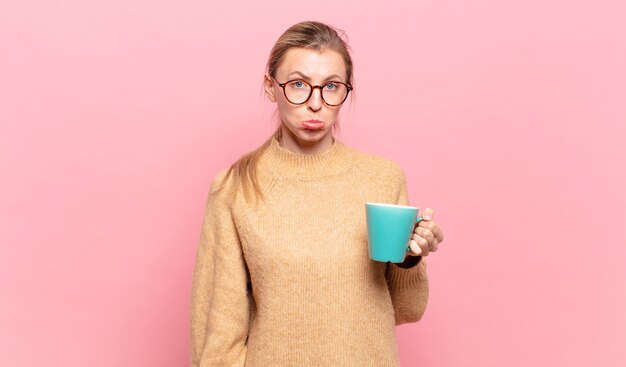 Jonge blonde vrouw voelt zich verdrietig en zeurt met een ongelukkige blik, huilend met een negatieve en gefrustreerde houding. koffie concept
