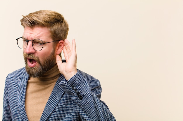 Jonge blonde zakenman die ernstig en nieuwsgierig kijkt