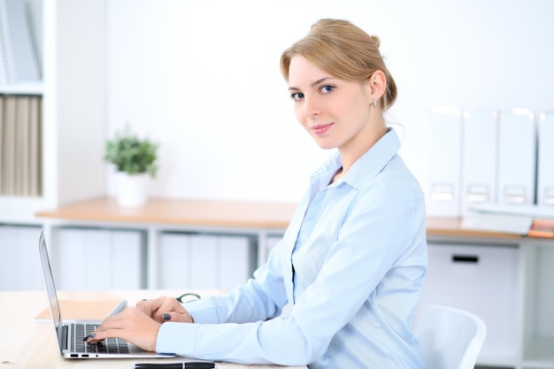 Jonge blonde zakenvrouw met laptop op kantoor Bedrijfsconcept