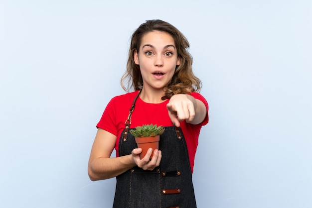 Jonge blondevrouw die een bloempot nemen en aan de voorzijde richten