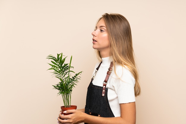 Jonge blondevrouw die een bloempot nemen