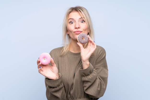 Jonge blondevrouw die een doughnut houden