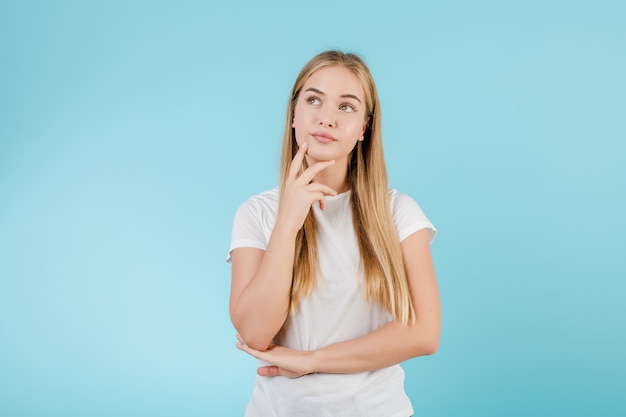 Jonge blondevrouw die geïsoleerd over blauw denken