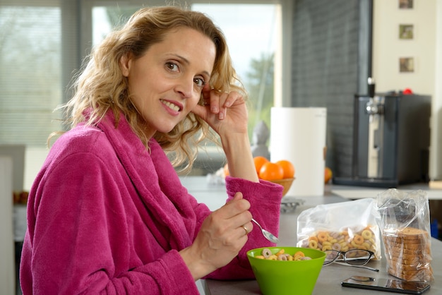 Jonge blondevrouw die graangewassen in de ochtend eten