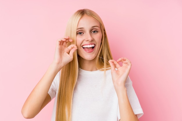 Jonge blondevrouw die haar tanden met een zijde schoonmaken