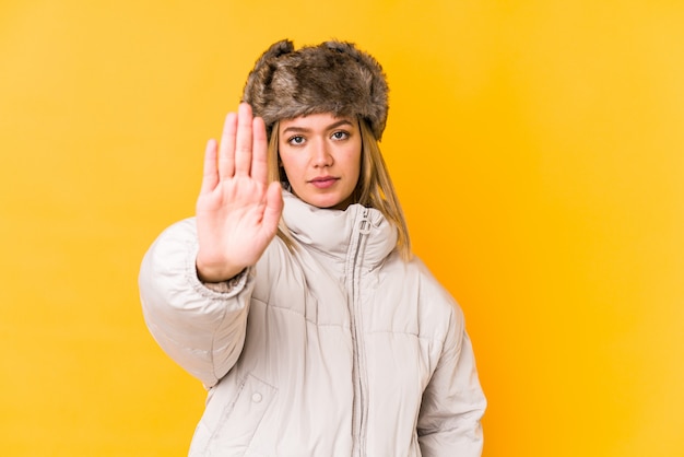 Jonge blondevrouw die op gele muur wordt geïsoleerd die zich met uitgestrekte hand bevindt die eindeteken toont