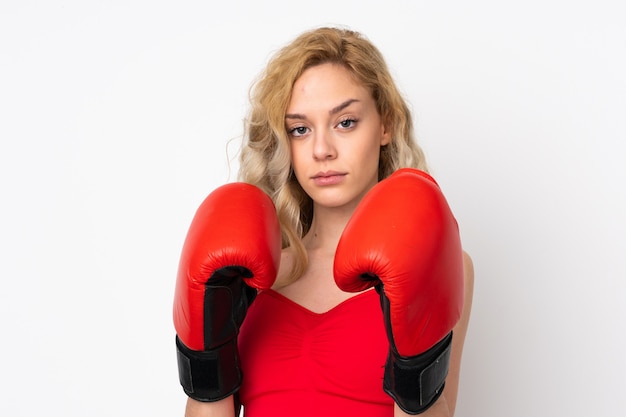 Jonge blondevrouw die op witte muur met bokshandschoenen wordt geïsoleerd